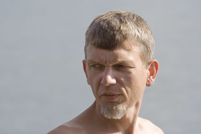 Shirtless man looking away against sky