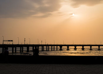 Silhouette pier over sea against sky during sunset