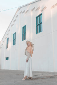 Woman standing against white building