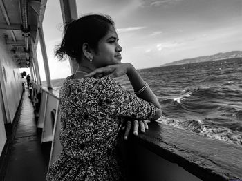 Side view of young woman standing against sea