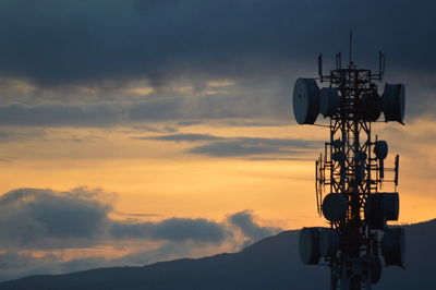 Low angle view of communications tower against sky at sunset