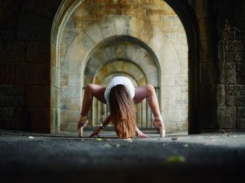 Woman performing ballet in old historic archway