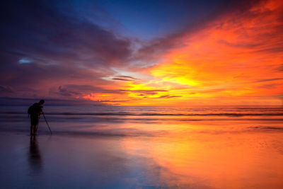 Silhouette man on beach against sky during sunset