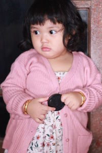 Portrait of cute girl holding pink while standing