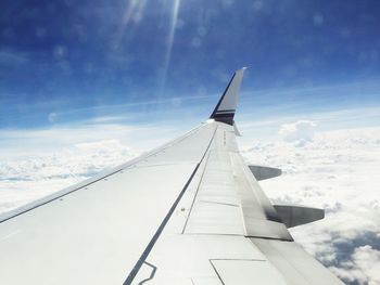 Airplane wing against cloudy sky