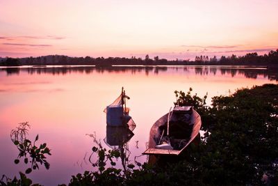 Boat moored in lake against sky during sunset