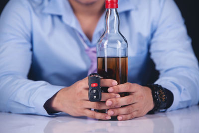 Midsection of man drinking glass on table