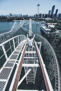 High angle view of person with arms raised sitting on rollercoaster in city