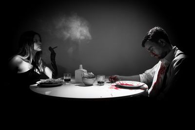 Woman smoking while having food in front of dead man