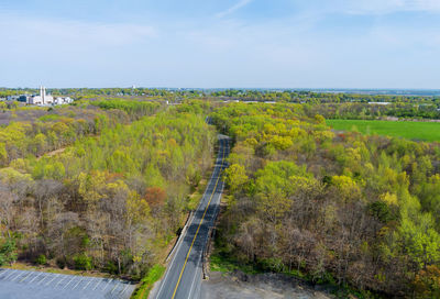 Road amidst trees and landscape against sky