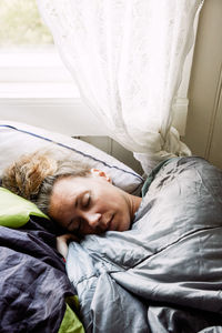 High angle view of mid adult woman sleeping on bed in cottage