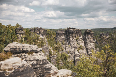 Scenic view of rocks and trees on landscape against sky