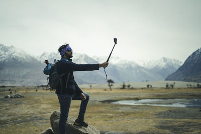 Handsome male travel blogger recording a video for vlog with his go pro action camera, making vlog.