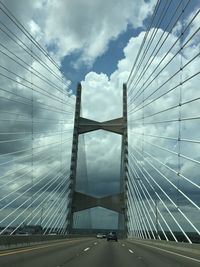 Low angle view of suspension bridge against cloudy sky