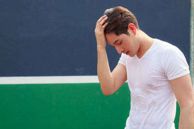 Young man looking away while standing against colorful wall