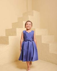 Portrait of young woman standing against wall