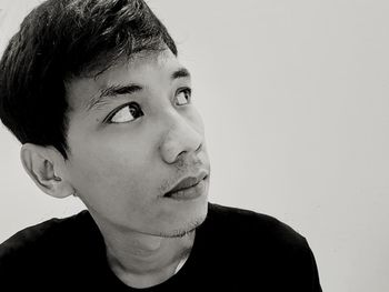 Portrait of young man looking away against white background