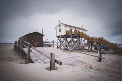 Lifeguard hut on beach by house against sky