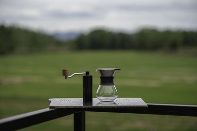 Table and chair on field against sky