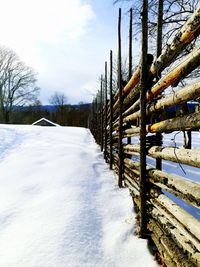 Snow covered field by trees against sky