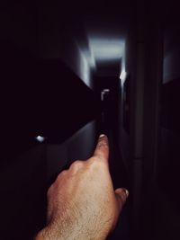Cropped hand pointing at dark corridor
