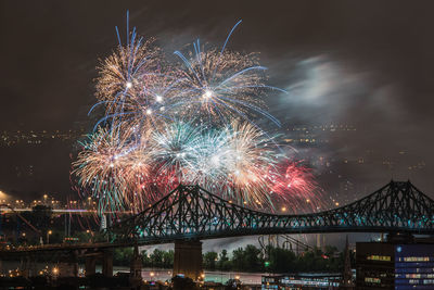 Low angle view of firework display over river against sky