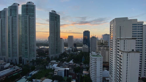 Modern buildings in city against sky during sunset