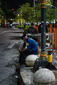 Rear view of man sitting on street