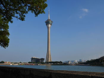 Tower amidst buildings against blue sky