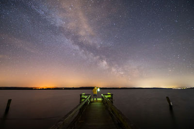 Pier over lake against sky at night