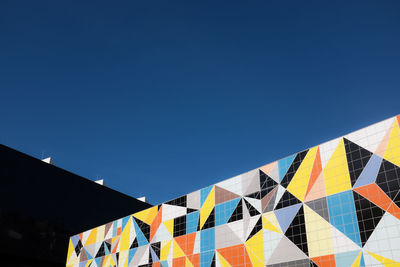 Low angle view of flags against clear blue sky