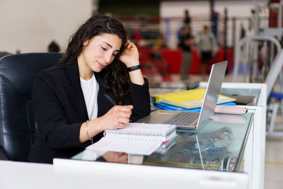 Smiling gym receptionist working at desk