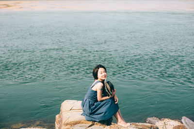 Woman sitting on rock at beach