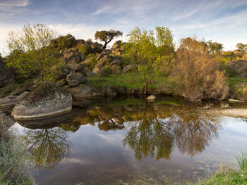 Reflection of rocks in lake against sky