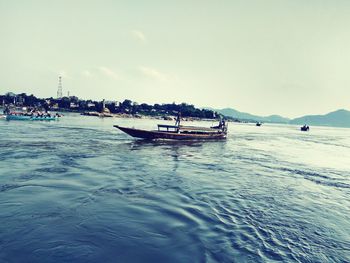 People on boat in sea against sky