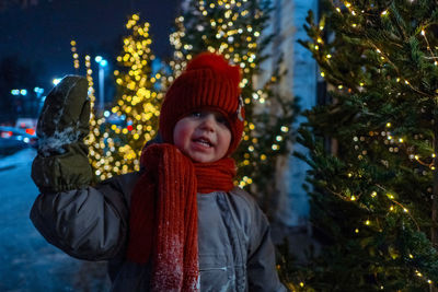Portrait of smiling boy in illuminated christmas tree during winter