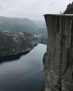 A man walks out onto preikestolen pulpit rock alone above a fjord