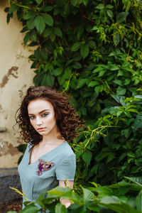 Portrait of young woman wearing make-up while standing against plants