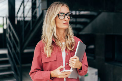 Attractive business woman stands against a modern urban backdrop.