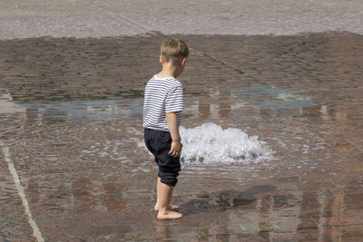 Rear view of boy standing in sea