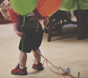Rear view of boy with helium balloons