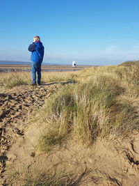 Full length of boy standing at beach against sky