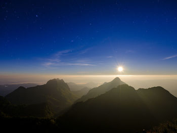 Scenic view of silhouette mountains against blue sky at night