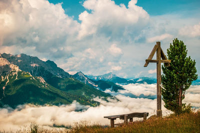 Wooden cross and wooden bench in the dolomites, italy.