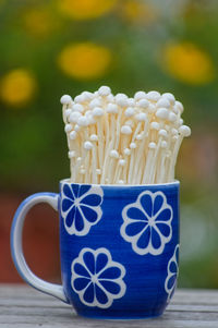 Close-up of white mushrooms in blue floral patterned cup on table