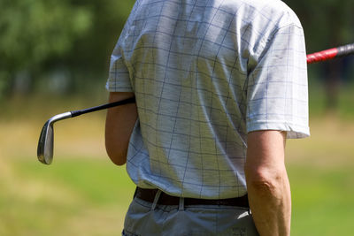 Rear view of man holding umbrella while standing outdoors