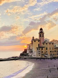 Building by sea against sky during sunset