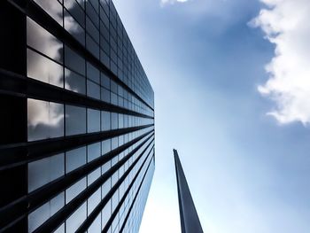 Low angle view of modern building against cloudy sky