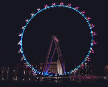 Illuminated ferris wheel in city at night
