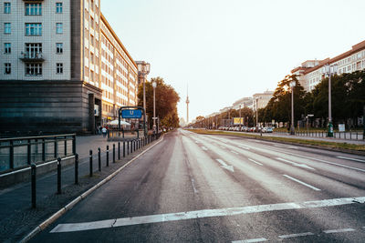 Road by buildings against sky in city